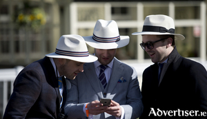 Racegoers looks a smartphone as they attend the final day of the Grand National Festival horse race meeting at Aintree Racecourse in Liverpool, Northern England on April 11, 2015. The annual three day meeting culminates in the Grand National which is run over a distance of four miles and four furlongs (7,242 metres), and is the biggest betting race in the United Kingdom. AFP PHOTO / OLI SCARFF        (Photo credit should read OLI SCARFF/AFP/Getty Images)