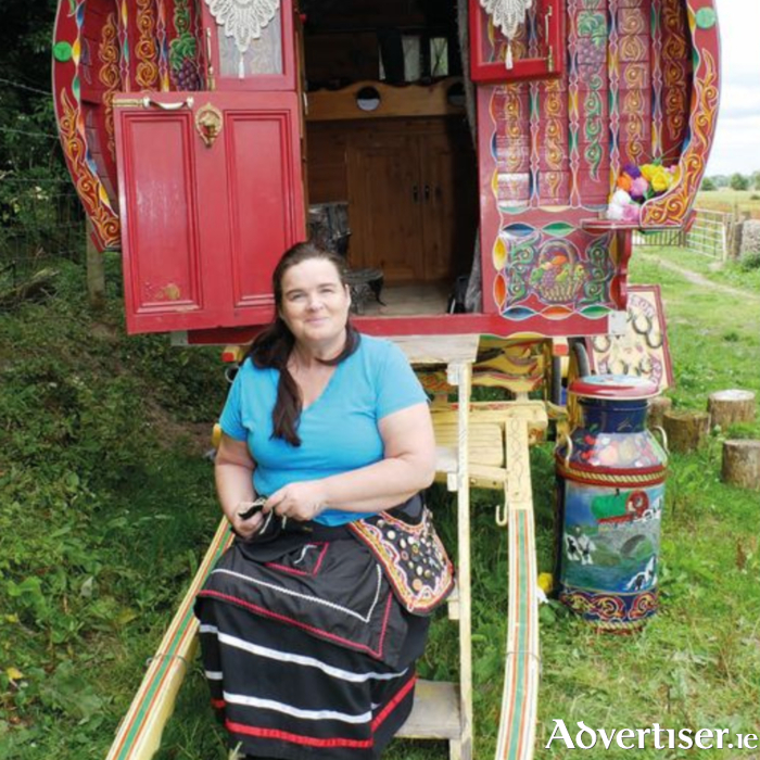 A Traveller woman sitting in front of a traditional, barrel top wagon.